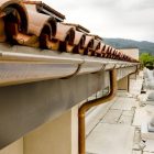 Terracotta roof tiles and metal rain gutter on a building rooftop.